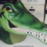 A smiling green Crocodile head mask with visible teeth