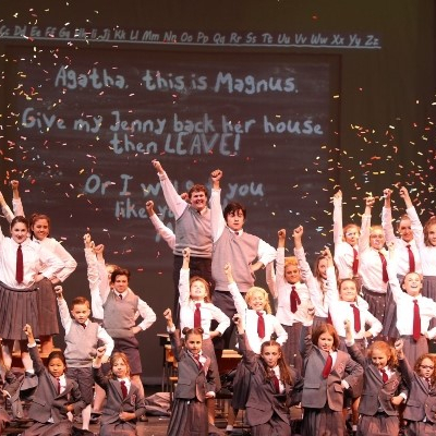 group of children in a play raising their first up