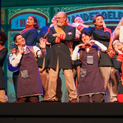Hello Dolly Harmonia Gardens ensemble in coordinated navy and red period costumes