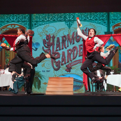 Hello Dolly Harmonia Gardens performers dancing in coordinated period costumes on stage