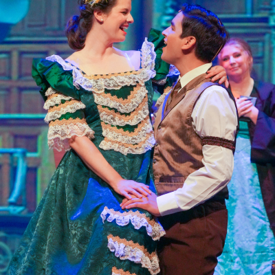 Hello Dolly performers in green and brown period costumes during a stage scene